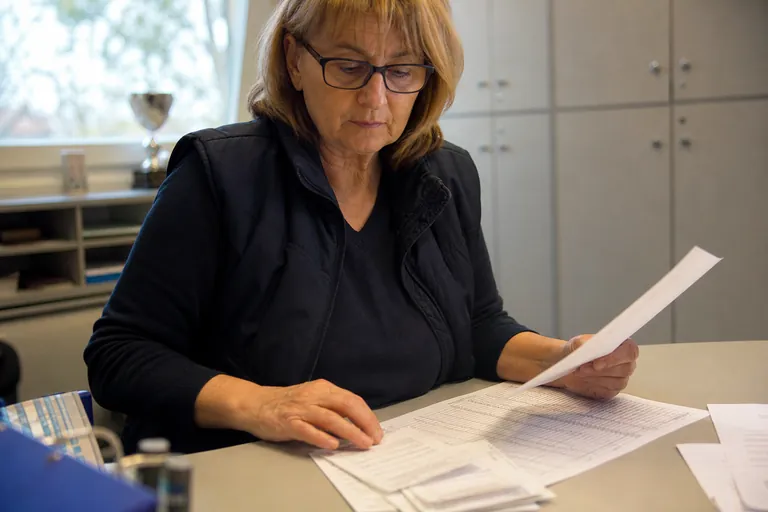 Kassenwartin prüft Unterlagen zu Trainervergütungen an einem Schreibtisch
