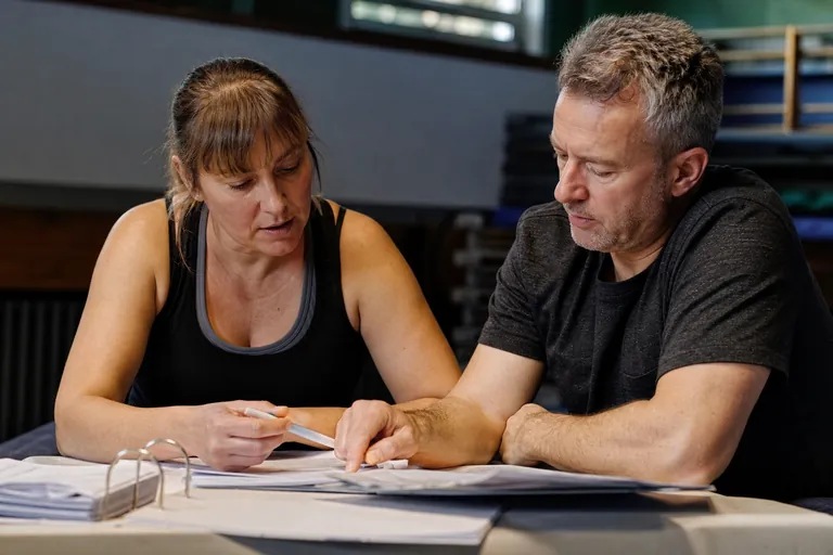 Trainerin und Kassenwart besprechen Vergütung und Trainingszeiten in einer Sporthalle